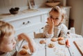 Two small toddler children sitting at the table, decorating and eating cakes at home. Royalty Free Stock Photo