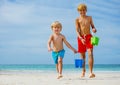 Two happy smiling boys run with water buckets from sea waves Royalty Free Stock Photo