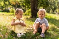 Two happy smiling cheerful toddler preschool twins siblings children brother sister boy girl sitting together on grass Royalty Free Stock Photo