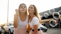 Two happy smiling girl friends blowing soap bubbles on shopping mall car parking Royalty Free Stock Photo