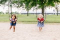 Two happy smiling little toddlers girls friends swinging on swings at playground outside Royalty Free Stock Photo