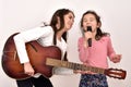 Two sisters with a microphone and the vintage acoustic guitar fooling around and singing