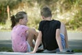 Two happy smiling teenage children, boy and girl sitting outdoors resting, having fun on summer sunny day Royalty Free Stock Photo