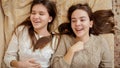 Two happy smiling teenage girls relaxing on bed and chatting. Teens having fun and good time together Royalty Free Stock Photo