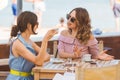 Two happy smiling women drinking espresso coffee and talking chatting in Italian beach restaurant or cafe Royalty Free Stock Photo