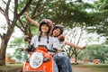 Two happy student girls riding motorbike with airplane hand gesture