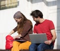 Two happy students sitting outdoors with lap top computer Royalty Free Stock Photo