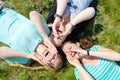 Two happy teen girls lying on green grass and holding hands