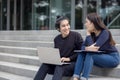 Two happy teenage students studying homework with a copybook sitting on stairs outside Royalty Free Stock Photo