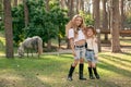 Two happy tween girls standing on green lawn in park on background of grazing pony Royalty Free Stock Photo
