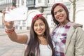 Two happy woman friends taking a selfie in the street. Royalty Free Stock Photo