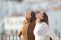 Happy women breathing fresh air in a balcony in winter