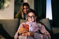 Two happy women friends using mobile phone in holidays at home on the sofa Royalty Free Stock Photo