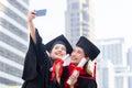 Two happy women in graduation gowns making selfie, Capturing happy moments
