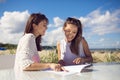 Two happy women sitting at cafe table on beach reading menu Royalty Free Stock Photo