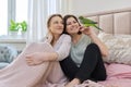 Two happy women sitting together on the bed with pet green parrot Royalty Free Stock Photo