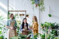 Two happy workers, male and female dressed as gardeners of a pot, decor and flower shop work serving a female customer Royalty Free Stock Photo