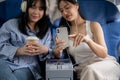 Two happy young Asian female friends passengers are enjoying talking together during the flight Royalty Free Stock Photo