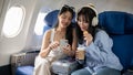 Two happy young Asian female friends passengers are enjoying talking together during the flight Royalty Free Stock Photo