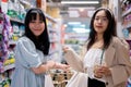 Two happy young Asian women shop together in a grocery store, walking with a shopping cart Royalty Free Stock Photo