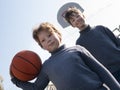 Two happy young boys playing basketball outdoors on a sports field Royalty Free Stock Photo