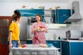 Two happy young Caucasian women cook together in the kitchen. The concept of LGBT couples and family cooking