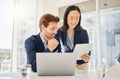 Two happy young diverse colleagues working together on a digital tablet in an office. Confident asian businesswoman Royalty Free Stock Photo