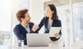 Two happy young diverse colleagues working together on a digital tablet in an office. Confident asian businesswoman and Royalty Free Stock Photo