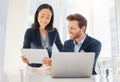 Two happy young diverse colleagues working together on a digital tablet in an office. Confident asian businesswoman and Royalty Free Stock Photo