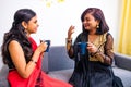 Two happy young female friends in with coffee cups in the living room at home Royalty Free Stock Photo