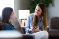 Two happy young female friends conversing in living room at home.