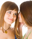 Two happy young girlfriends telling secret