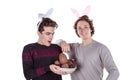 Two happy young men in a rabbit-like ears holding up basket with eggs. Happy Easter. Isolated on white background Royalty Free Stock Photo