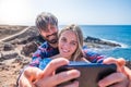 Two happy young people having fun together and taking a selfie looking at the phone - beach lifestyle and enjoying vacations and Royalty Free Stock Photo