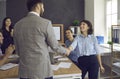 Two happy young people shaking hands in a business meeting with their colleagues Royalty Free Stock Photo