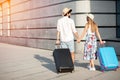 Two happy young tourists walking hand in hand away from the camera, pulling suitcases Royalty Free Stock Photo