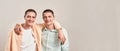 Two happy young twin brothers hugging and smiling at camera while posing together isolated over beige background Royalty Free Stock Photo