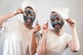 Two happy young woman apply clay mask on face enjoy free time Royalty Free Stock Photo