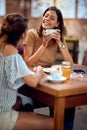 Two happy young woman enjoying coffee together in cafe