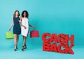 Two happy young woman hand holding shopping bag with cashback promotion isolated over blue background Royalty Free Stock Photo