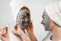 Two happy young woman apply clay mask on face enjoy free time Royalty Free Stock Photo