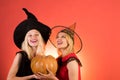 Two happy young women in black and red dresses, costumes witches halloween on party over orange background. Two Royalty Free Stock Photo