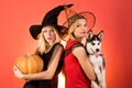 Two happy young women in black and red dresses, costumes witches halloween on party over orange background. Two Royalty Free Stock Photo