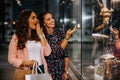 Two happy young women with shopping bags having fun and pointing finger in the shop window Royalty Free Stock Photo