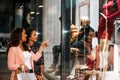 Two happy young women with shopping bags having fun and pointing finger in the shop window Royalty Free Stock Photo