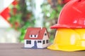 Two hard hats of different colors and a small house model