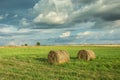 Two hay circles on a green meadow and cloudy sky. Polish country Royalty Free Stock Photo