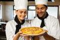 Two head chef presenting a pizza Royalty Free Stock Photo