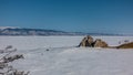 A two-headed granite rock, devoid of vegetation, rises above a frozen lake.