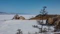 A two-headed rock, devoid of vegetation, rises above a frozen lake.